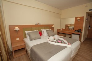 A hotel room with a bed, bedside tables, a desk, a mirror, and a small refrigerator. - Rhodos Horizon Marina (Rhodes)
