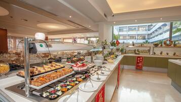 A buffet area with various food items and a view of a modern building in the background.