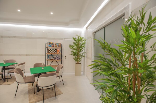A modern interior with a dining area, a bookshelf, and a large potted plant.