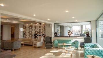 A modern lobby with a geometric wall design, plush seating, and a large window offering a city view.