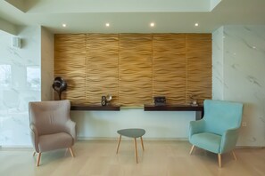 A reception area with a modern design, featuring a wooden textured wall, marble flooring, and two chairs.