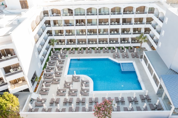 A multi-story hotel with a central swimming pool surrounded by sun loungers and a small garden area. - Rhodos Horizon Marina (Rhodes)