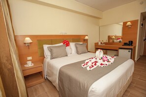 A hotel room with a bed, bedside tables, a mirror, a desk, and a small refrigerator. - Rhodos Horizon Marina (Rhodes)