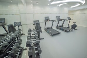 A gym with treadmills, dumbbells, and weight machines.