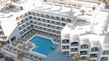Ett hotell med flera balkonger, en central pool och en takterrass.
