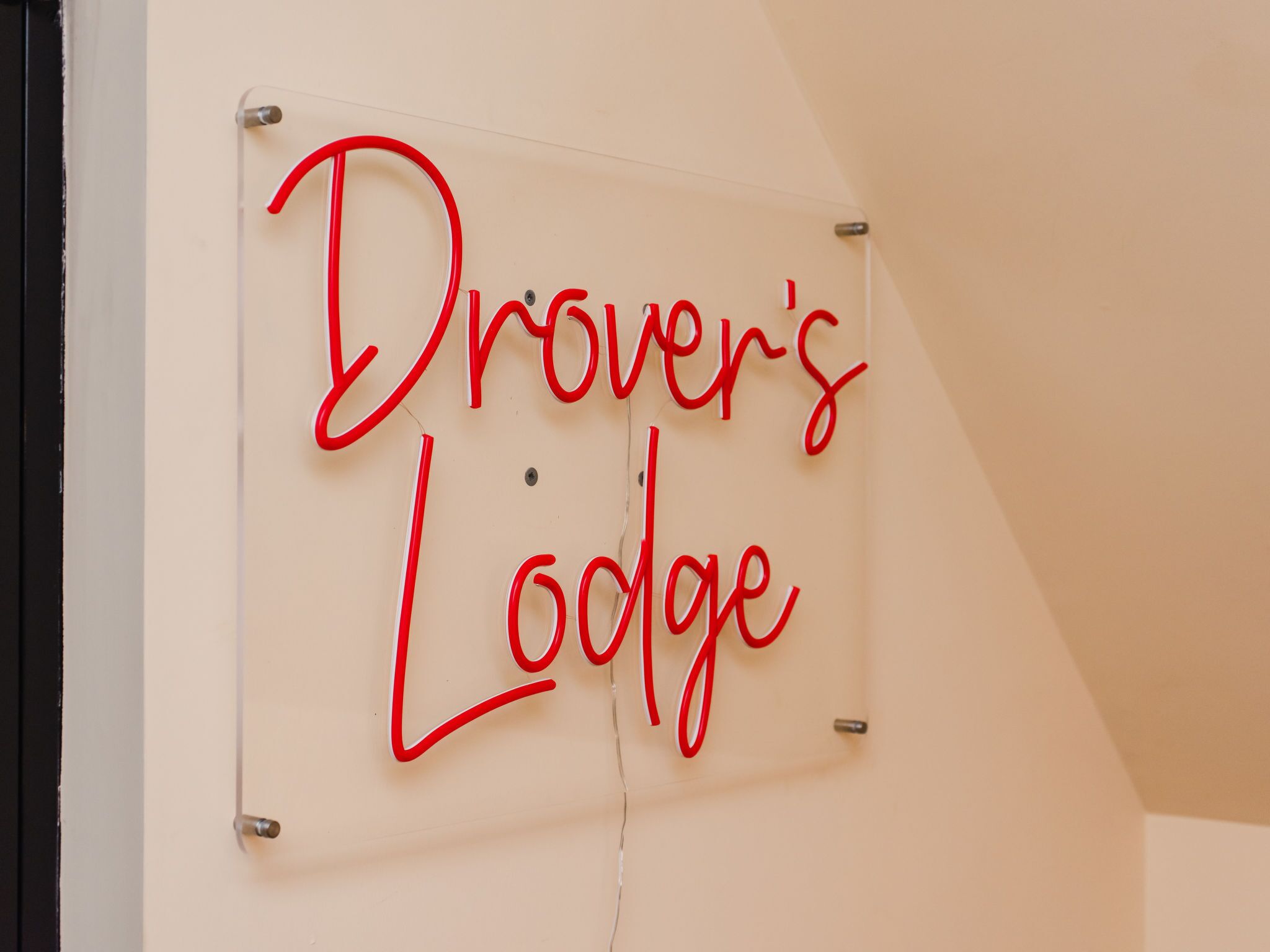 A clear glass sign with red lettering that reads "Driver's Lodge."