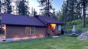 A wooden cabin with a porch, a small deck, and a table with an umbrella.