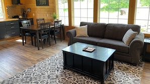 A cozy cabin interior with a dining area, a sofa, and a kitchen with a chimney.