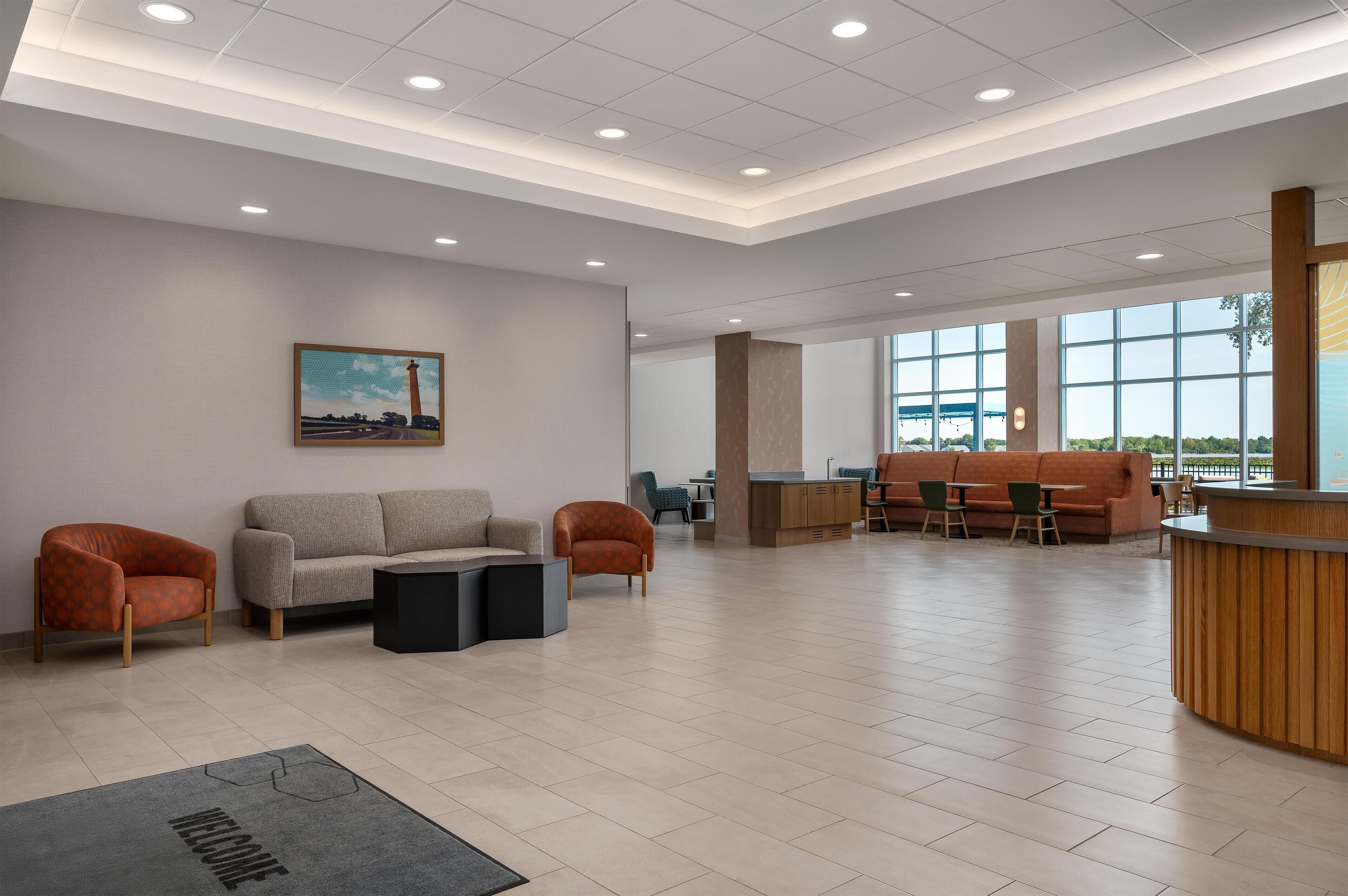 A spacious lobby with a reception desk, seating area, and large windows.