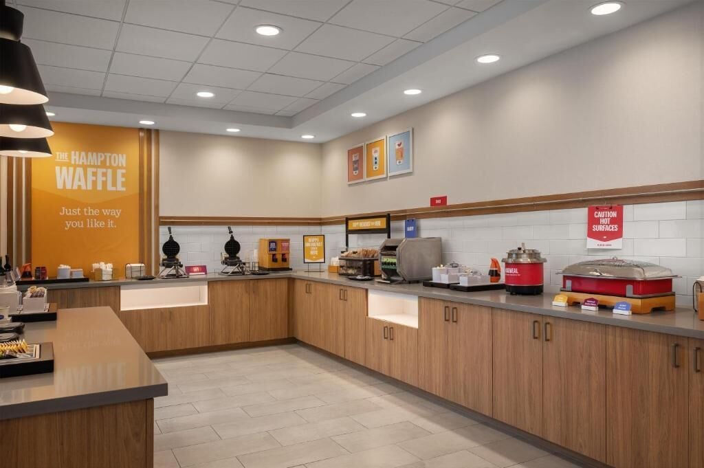 A modern kitchen area with a large sign for 'The Hampton Waffle' and a caution sign for hot surfaces.