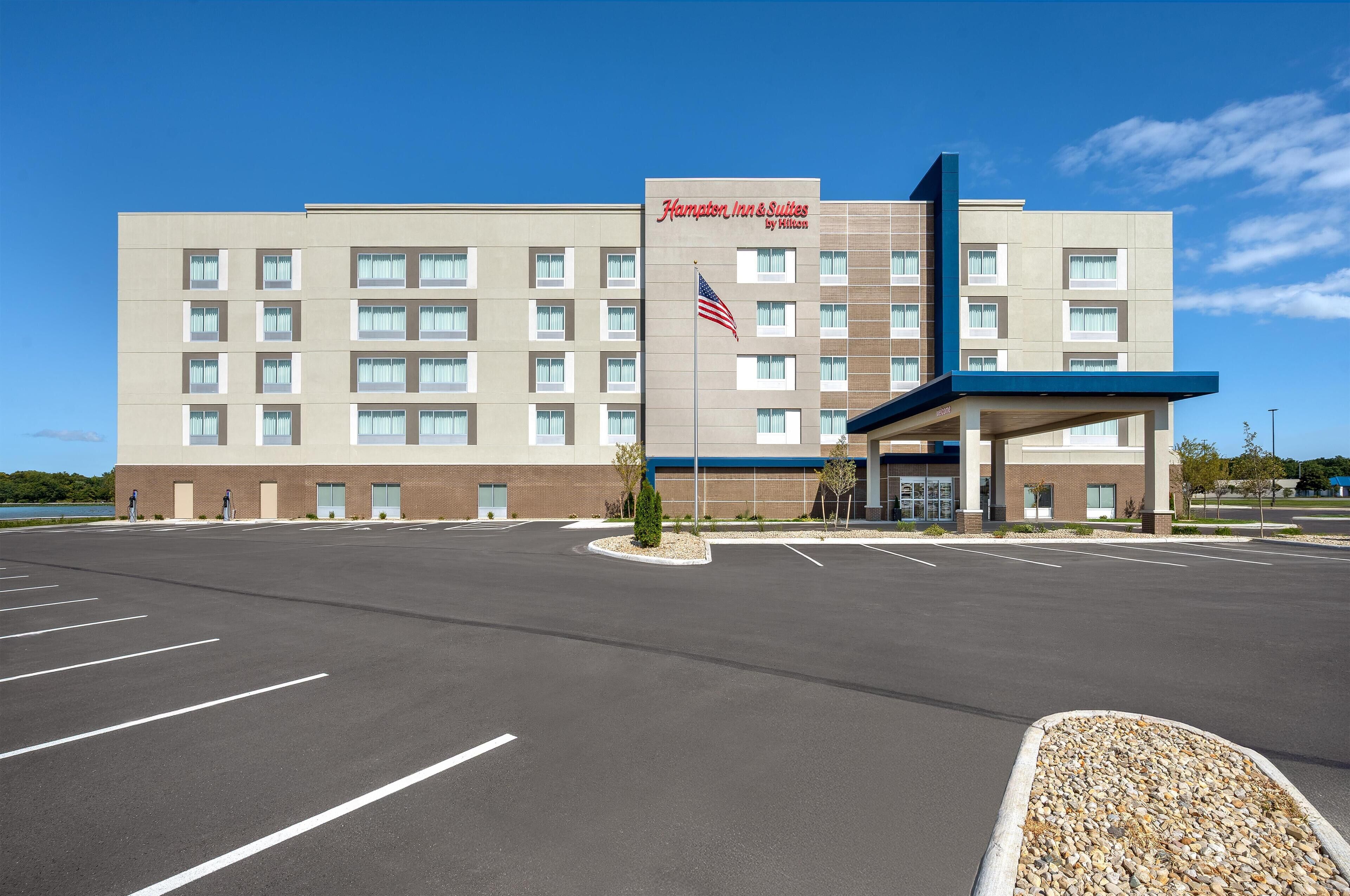 Un bâtiment de la chaîne Hampton Inn & Suites by Hilton, avec un parking situé devant.