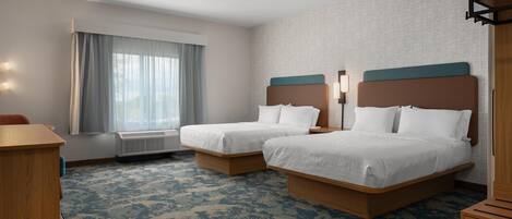 A hotel room with two beds, a desk, a chair, and a window with curtains.