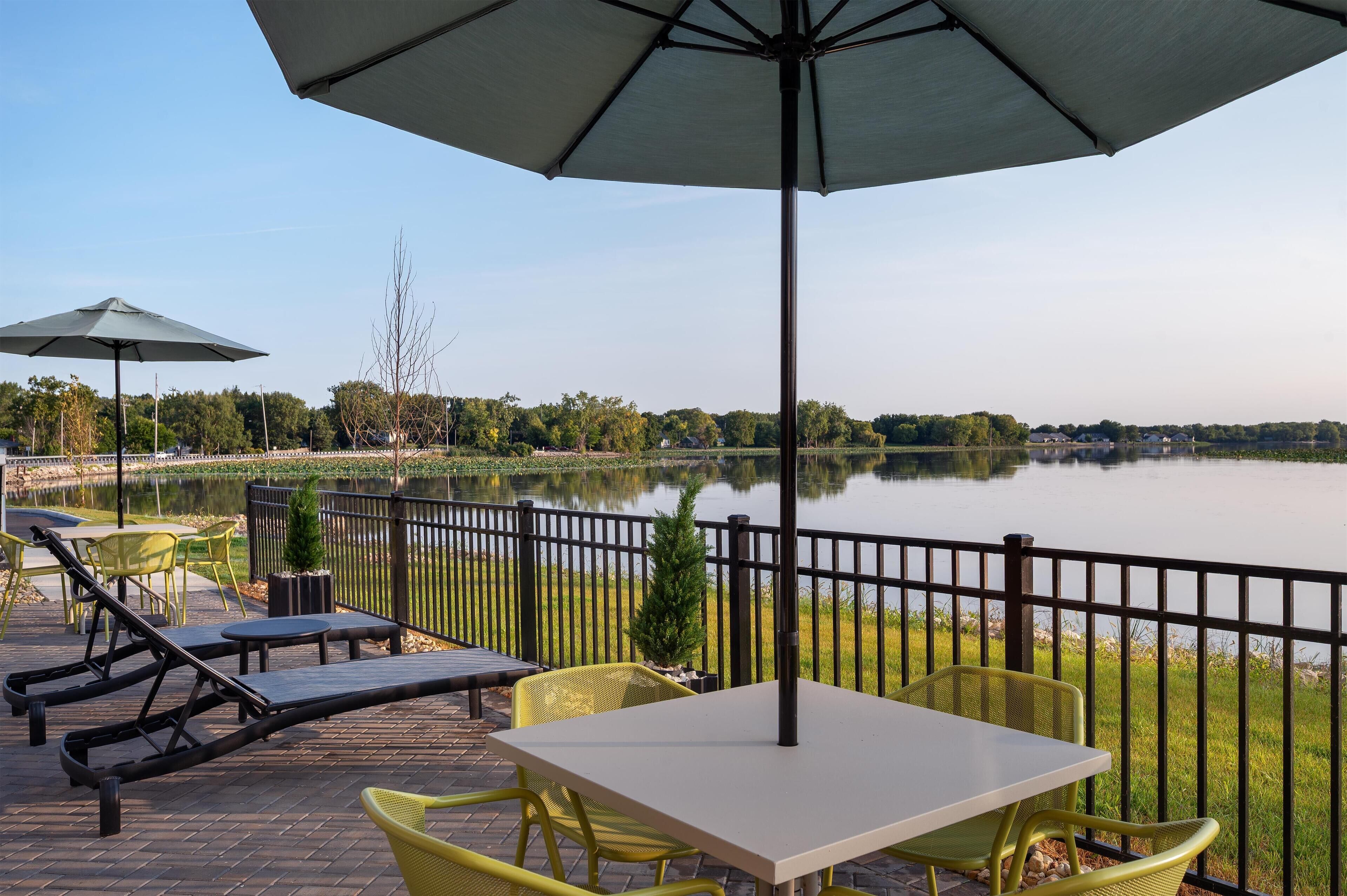 Un patio con mobiliario exterior, una mesa y vistas a un lago.