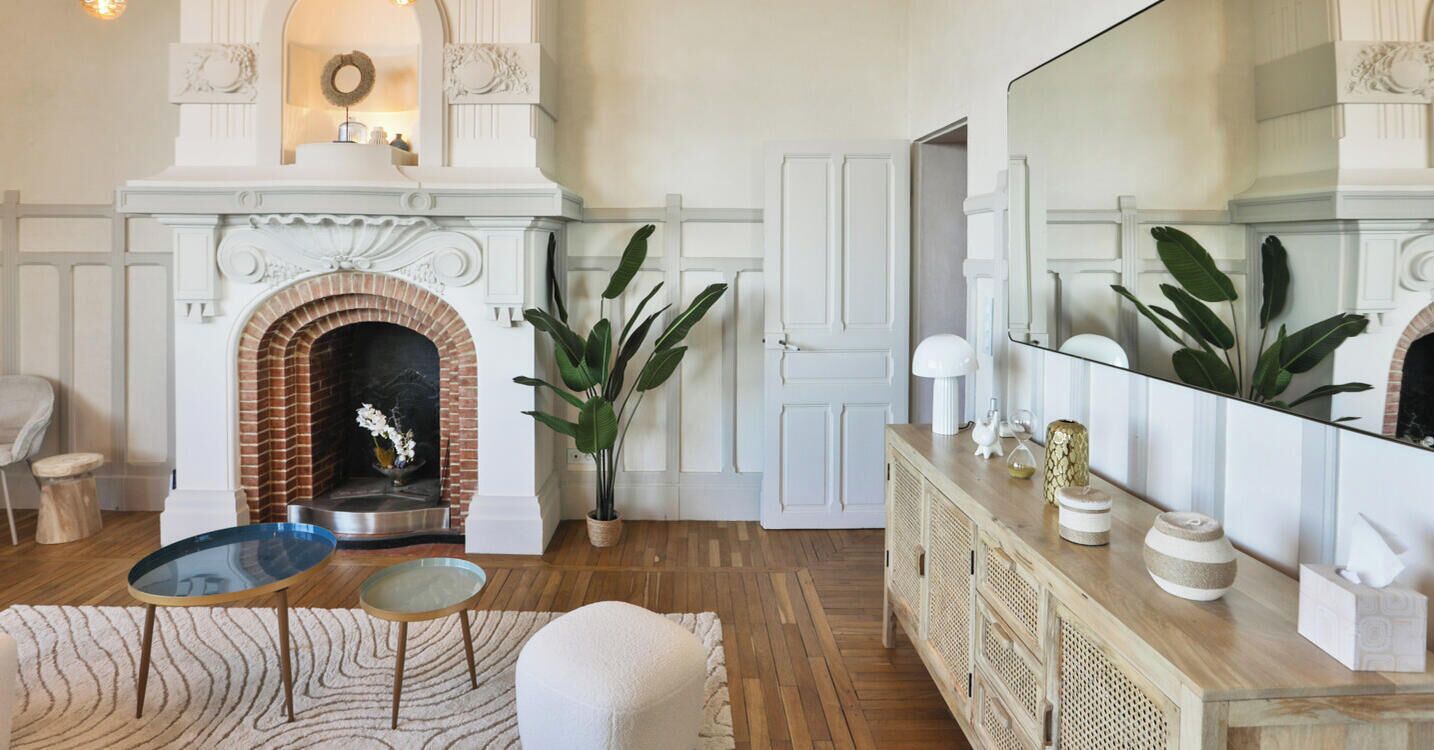 Un salon avec une cheminée, un grand miroir et un meuble en bois.