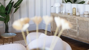 Een kamer met een witte houten kast, een klein rond tafeltje en een kamerplant.