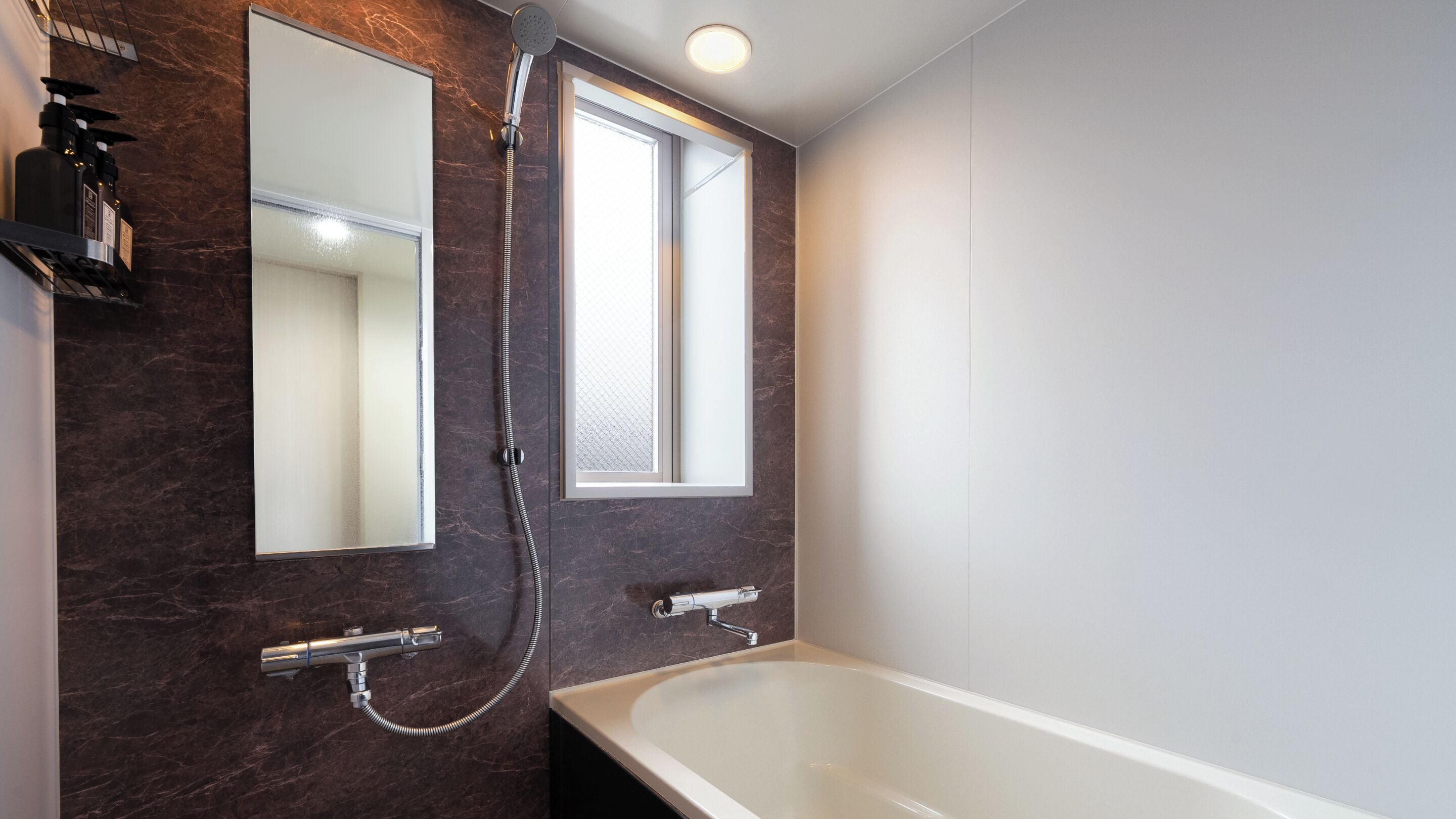 Un baño moderno con bañera, ducha y dos espejos.