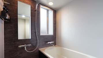 Un baño moderno con bañera, ducha y dos espejos.