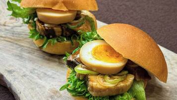 A sandwich with a half-cut egg on a bun, surrounded by greens and other fillings.