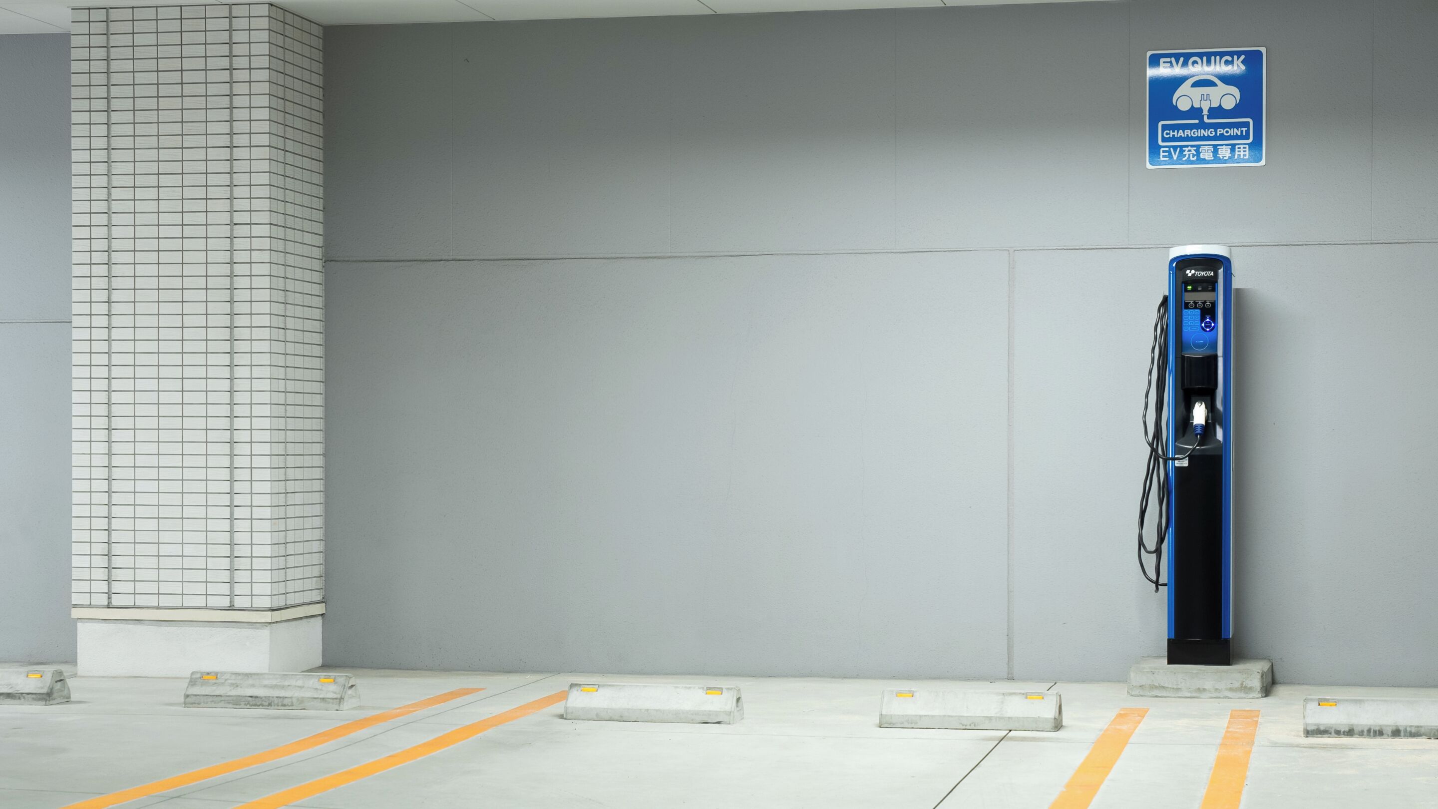 Een lege laadpaal voor elektrische voertuigen in een parkeergarage, met een bord dat aangeeft dat het een snellaadpunt is.