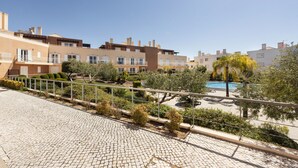 A residential area with multiple apartment buildings, a paved walkway, and a swimming pool.