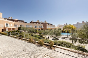 A residential area with multiple apartment buildings, a paved walkway, and a swimming pool.
