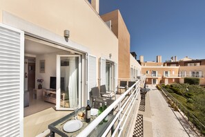 Un balcon avec une table dressée pour le repas, un canapé et une chaise.