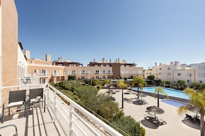 A hotel courtyard with a swimming pool, lounge chairs, and a view of the surrounding buildings. - Paradise: Private Balcony with Pool View (Cabanas de tavira)