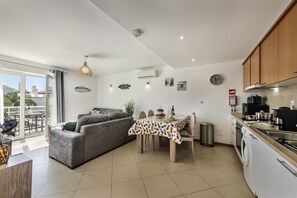 A modern kitchen with a dining area, a grey sofa, and a view of the outside. - Paradise: Private Balcony with Pool View (Cabanas de tavira)