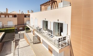 A residential building with a balcony, a staircase, and a view of neighboring buildings.