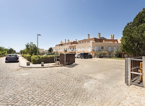 A residential street with a row of townhouses, cobblestone pavement, and parked cars.
