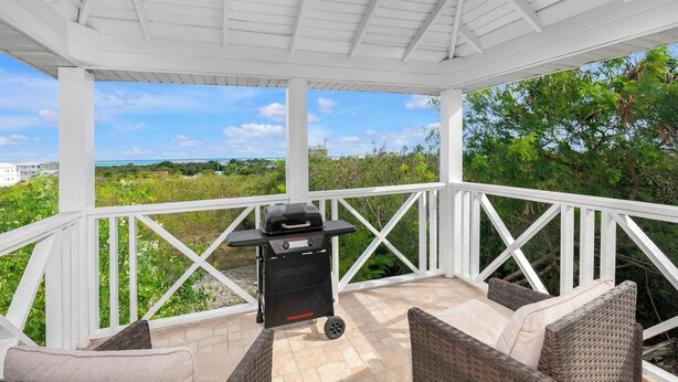 Un patio exterior con una parrilla, muebles de mimbre y vistas al paisaje.
