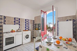 A compact kitchen with a washing machine, a stove, and a dining area with a table set for two.