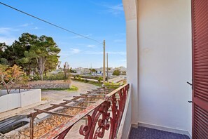 Ein Balkon mit Metallgeländer, einer Steinmauer und Blick auf ein Wohngebiet mit Häusern und Bäumen.