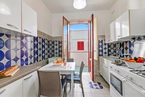 A kitchen with white cabinets, a dining table with chairs, a stove, and a refrigerator.