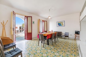 A dining area with a table set for four, surrounded by wicker chairs, a television, and a map on the wall.