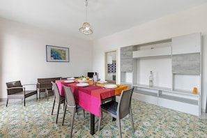 Un comedor con una mesa dispuesta para cuatro personas, rodeada de sillas de mimbre y un suelo de baldosas con diseño geométrico.