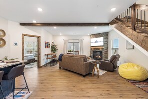 Ein modernes Wohnzimmer mit Kamin, Essbereich und einer Treppe.