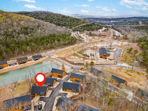 Una zona residencial con varias casas, un lago pequeño y un paisaje montañoso al fondo.