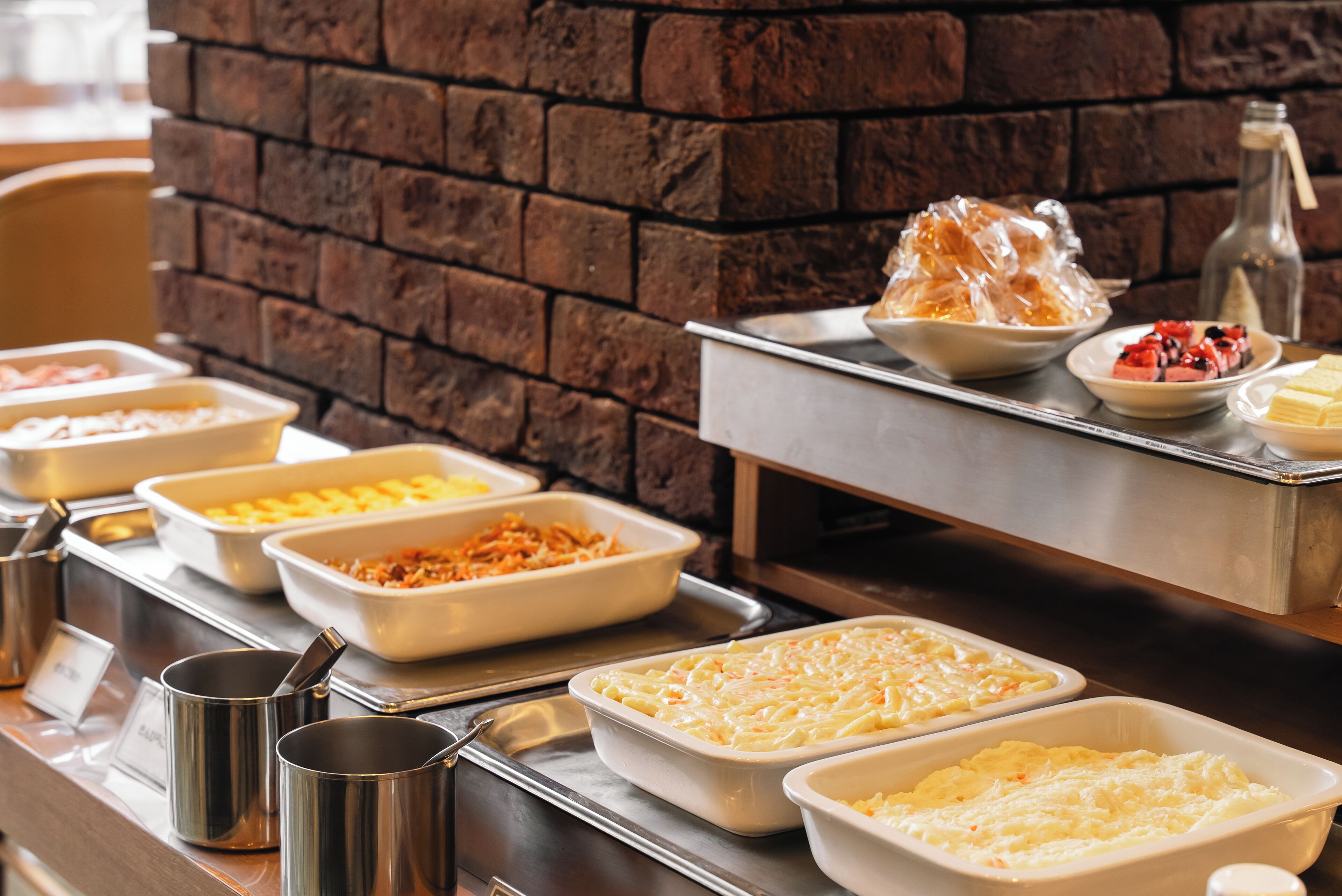 Een buffet met diverse gerechten en een bakstenen muur op de achtergrond.