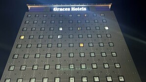A tall building with a sign reading "Graces Hotels" at the top. - Graces Hotels (Inzai)