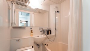A bathroom with a sink, mirror, shower, and a toilet. - Graces Hotels (Inzai)