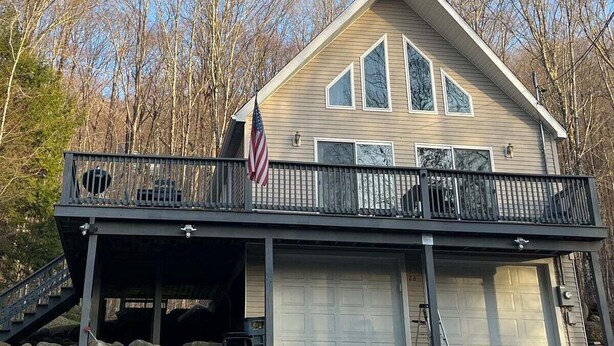 A two-story house with a balcony, a garage, and a flag. - Private Home in the White Mountains! (Campton)