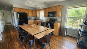 Enjoy cooking in this well-equipped kitchen with a central island, wooden cabinets, and a large window offering a view of the surrounding greenery.