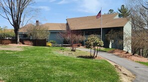 A building with a flag, a lawn, and a pathway.