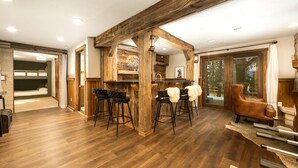 Ein rustikales Interieur mit Holzbalken, einer Bar mit Hockern und einer gemütlichen Sitzecke.