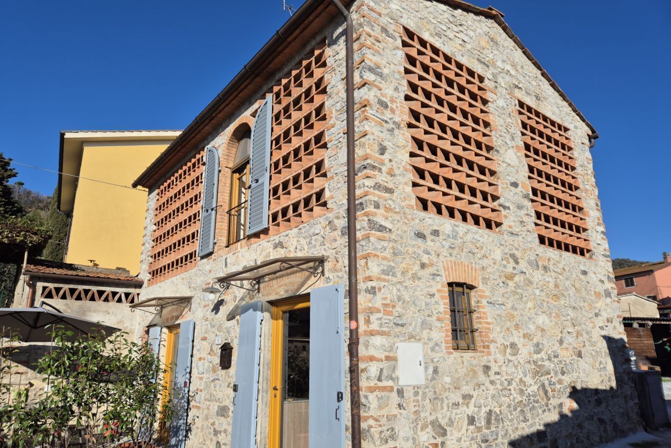 A stone building with a yellow facade and a wooden balcony.