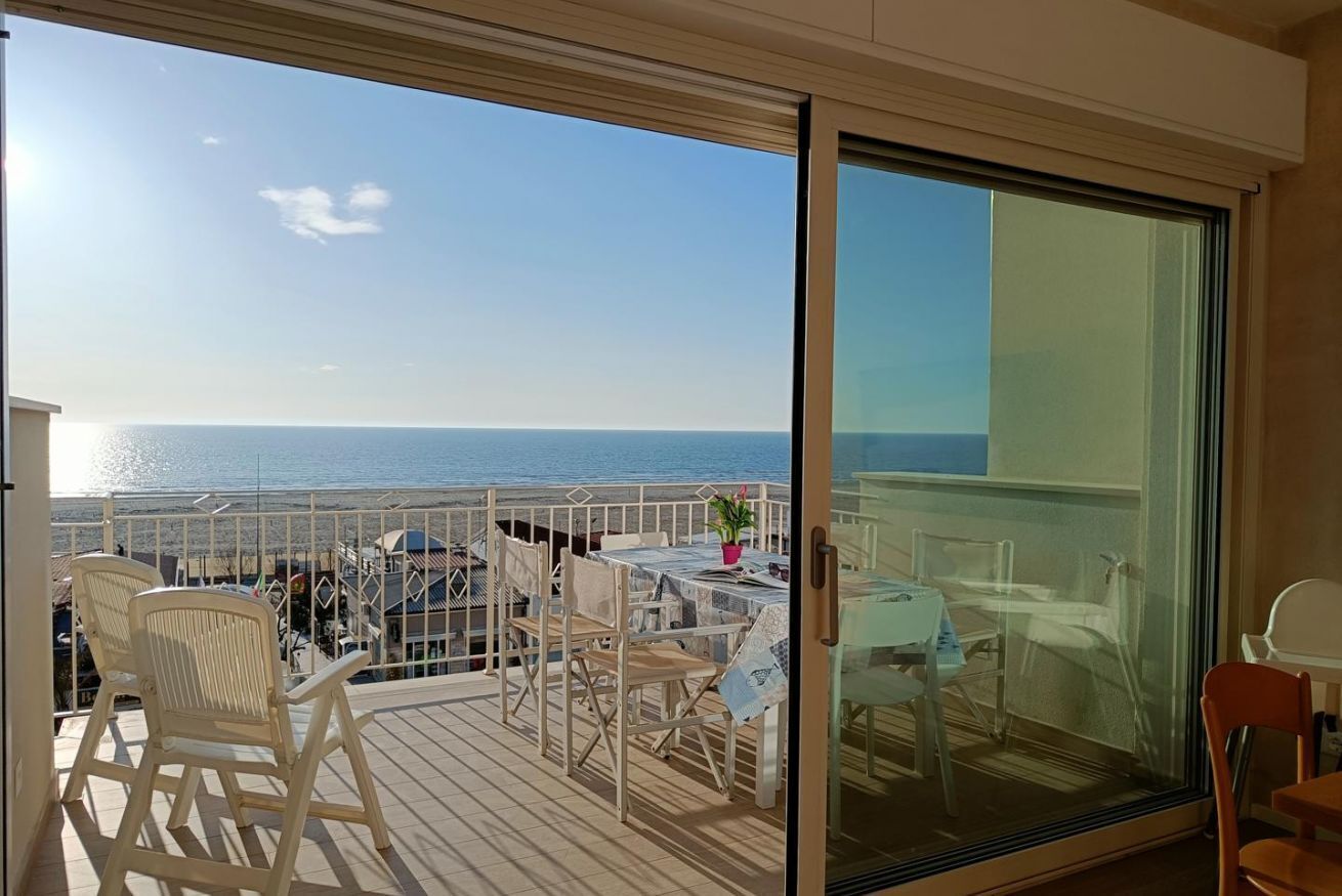 Un balcon donnant sur la mer, aménagé avec des chaises et une table.