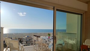 A balcony with a view of the sea, furnished with chairs and a table. -  Elegant and modern seafront flat in Lido di Camaiore, located on the 4th floor with lift, perfect for a relaxing and comfortable holiday.The flat boasts a large terrace with sea view, equipped with an awning and dining table, ideal for enjoying panorami (Camaiore)