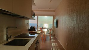A modern kitchen with a built-in stove, sink, and a dining area with a table and chairs. -  Elegant and modern seafront flat in Lido di Camaiore, located on the 4th floor with lift, perfect for a relaxing and comfortable holiday.The flat boasts a large terrace with sea view, equipped with an awning and dining table, ideal for enjoying panorami (Camaiore)