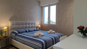 A bedroom with a large bed, bedside lamps, a window, and a small table with a vase of flowers. -  Elegant and modern seafront flat in Lido di Camaiore, located on the 4th floor with lift, perfect for a relaxing and comfortable holiday.The flat boasts a large terrace with sea view, equipped with an awning and dining table, ideal for enjoying panorami (Camaiore)